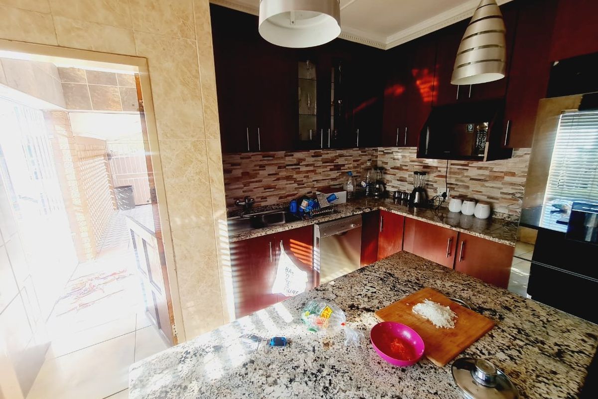A functional kitchen featuring dark wood cabinetry, granite countertops, a tiled backsplash, and direct access to an outdoor patio area.