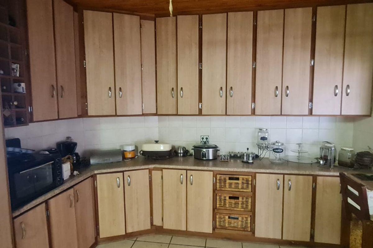A functional kitchen featuring extensive laminate cabinetry, tiled backsplash, and tiled flooring, offering a classic layout with ample storage space.