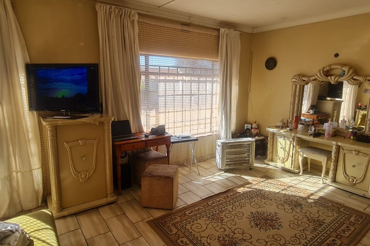Spacious bedroom featuring tiled flooring and large windows with security gates, offering a functional layout ready for modernization.