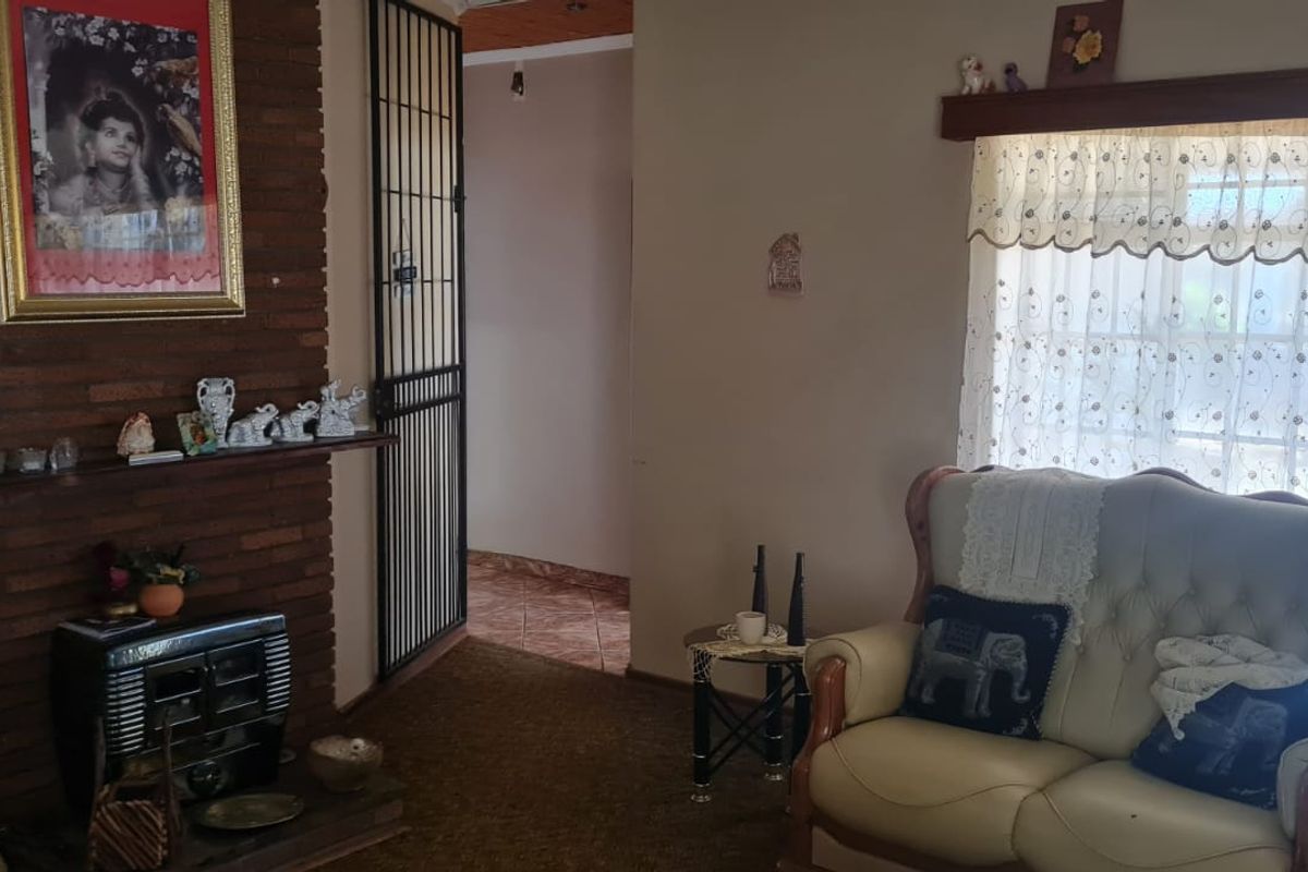 Living room featuring a brick fireplace, security gate, and large window, offering a traditional layout with potential for modernization.
