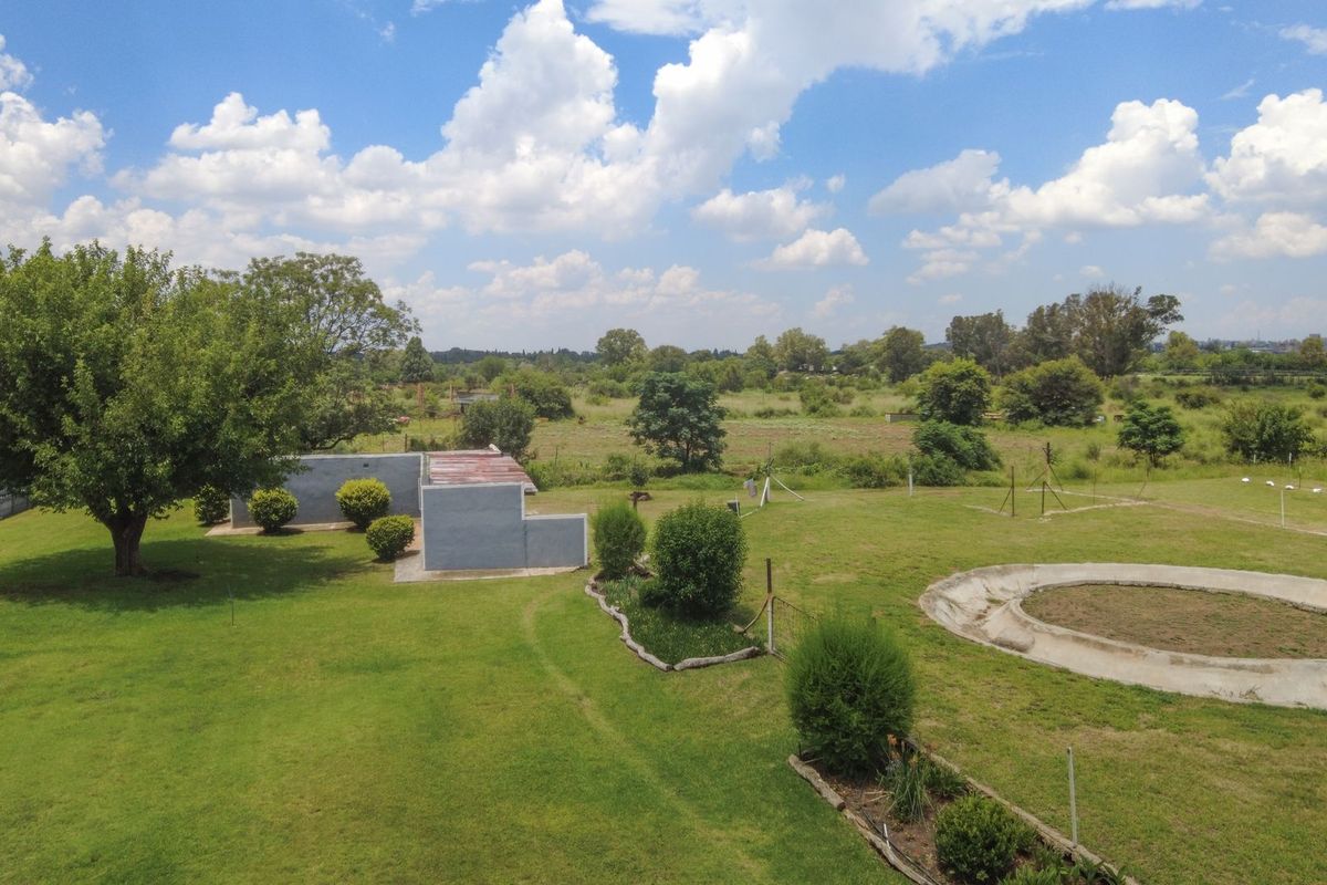 Aerial view of the farm grounds featuring a large lawn, an outbuilding, and a circular concrete water reservoir set within the open landscape.