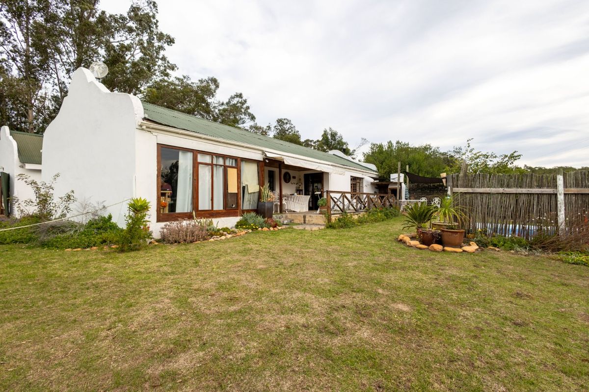 Rear view of a farm-style cottage featuring a covered patio, timber window frames, and a spacious garden area.