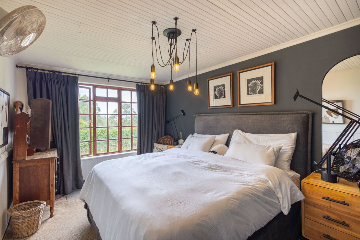 A well-maintained bedroom featuring a beadboard ceiling, timber-framed windows, and modern pendant lighting, creating a cozy and inviting atmosphere.