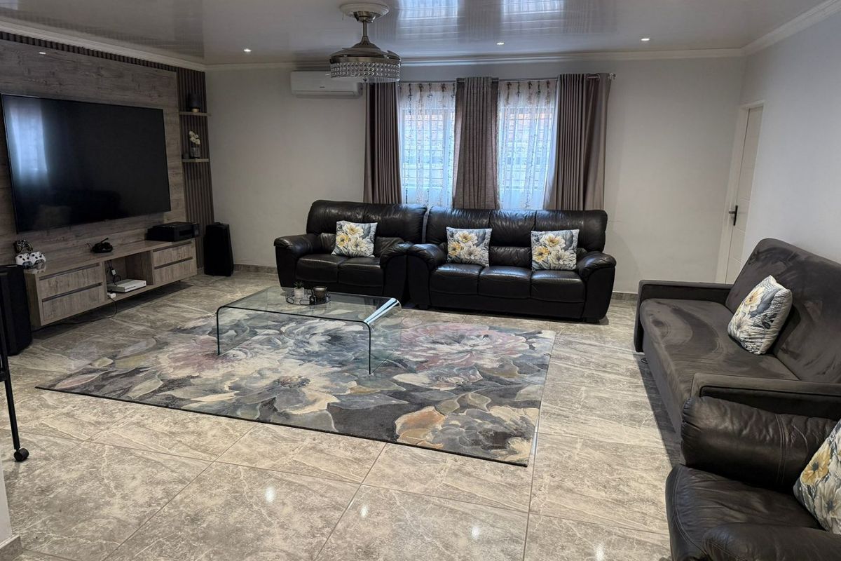 Spacious living room featuring polished tile flooring, a built-in media wall unit, recessed lighting, and a ceiling fan.