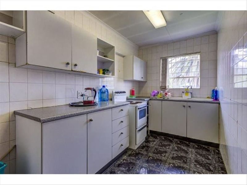 A functional kitchen featuring built-in cabinetry, laminate countertops, a freestanding stove, and tiled finishes throughout, offering potential for modernization.