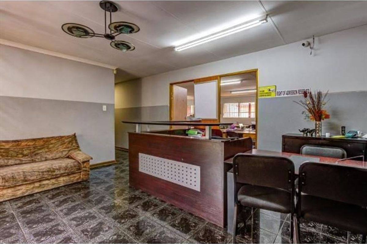 Commercial reception area featuring a built-in reception desk, tiled flooring, and fluorescent lighting, providing a functional entry point for the office space.