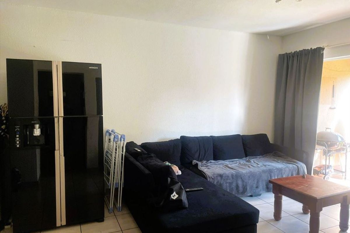A living room area featuring tiled flooring and a sliding door providing access to an outdoor space.
