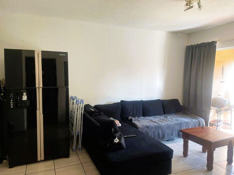 A living room area featuring tiled flooring and a sliding door providing access to an outdoor space.