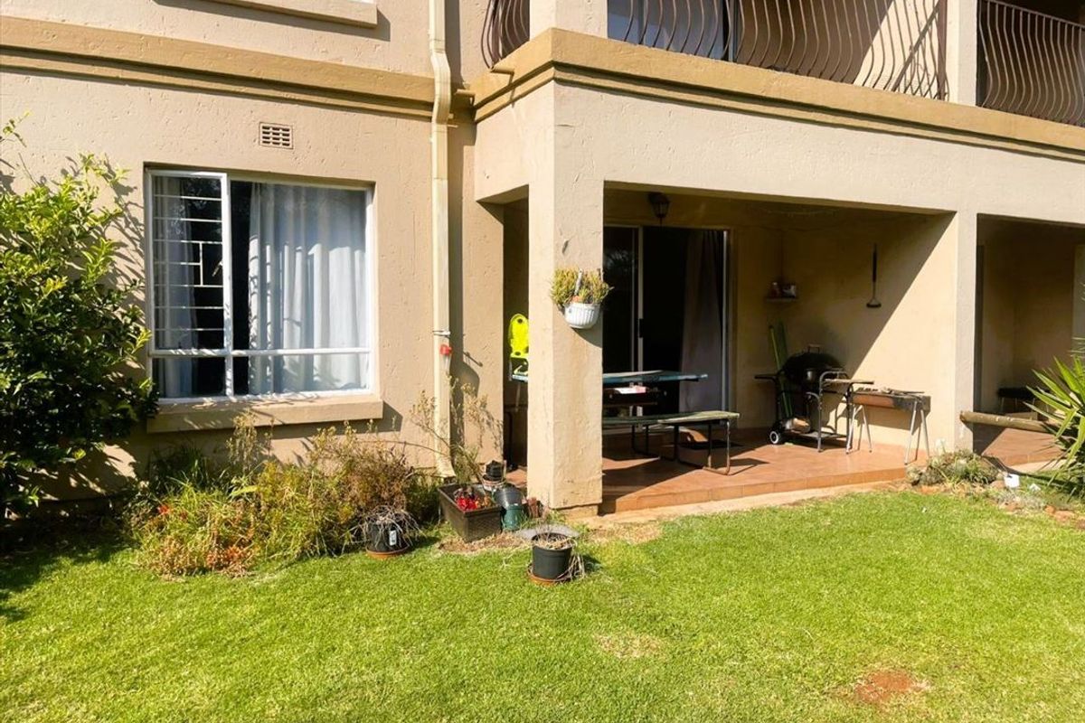 Rear view of the townhouse featuring a covered patio, tiled flooring, sliding door access, and an upper-level balcony with metal railings.