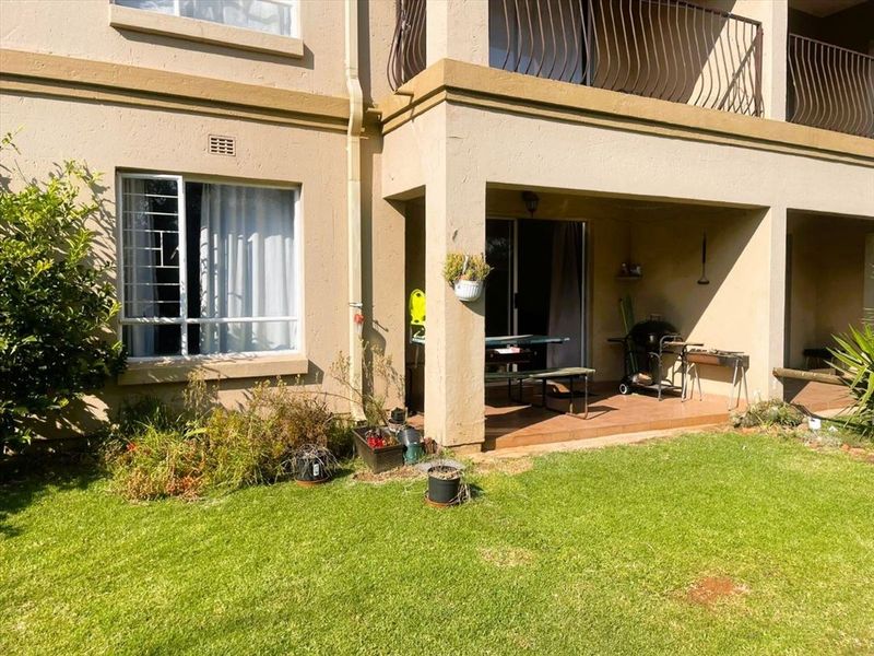Rear view of the townhouse featuring a covered patio, tiled flooring, sliding door access, and an upper-level balcony with metal railings.
