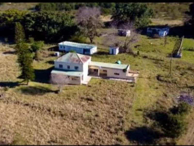 Aerial view of a farm property featuring a main dwelling, outbuildings, and surrounding open land.