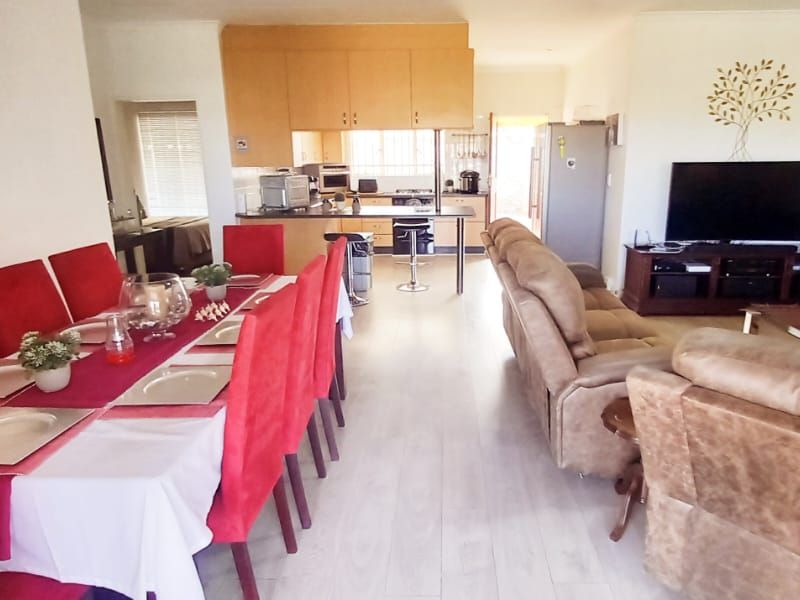 Spacious open-plan living area featuring a dining space and a functional kitchen with built-in cabinetry and a breakfast bar.