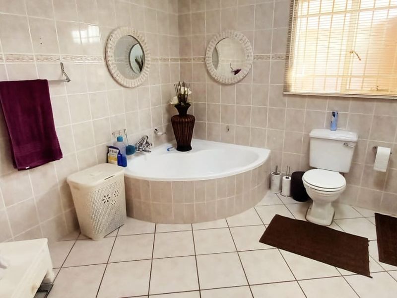 A functional bathroom featuring a corner bathtub, tiled walls and flooring, a toilet, and a separate shower enclosure.
