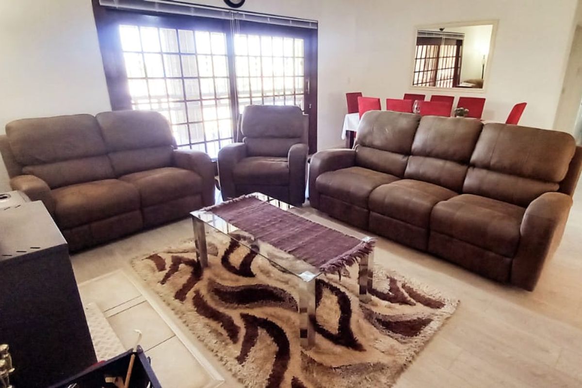 Spacious living room featuring a freestanding fireplace, light laminate flooring, and large sliding glass doors providing access to the outdoor area.