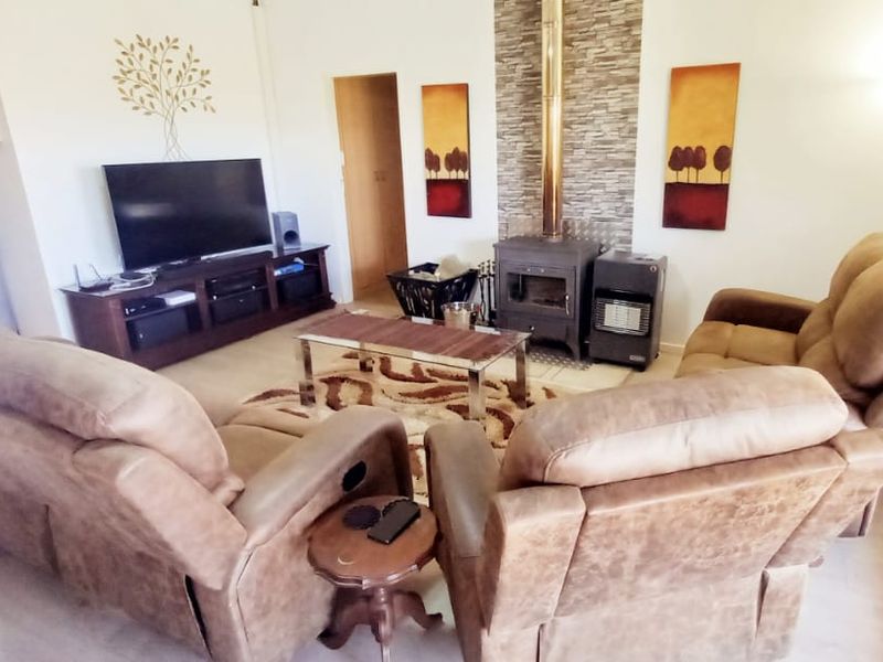 A comfortable living room featuring a stone-clad fireplace, tiled flooring, and access to the outdoors through classic french doors.