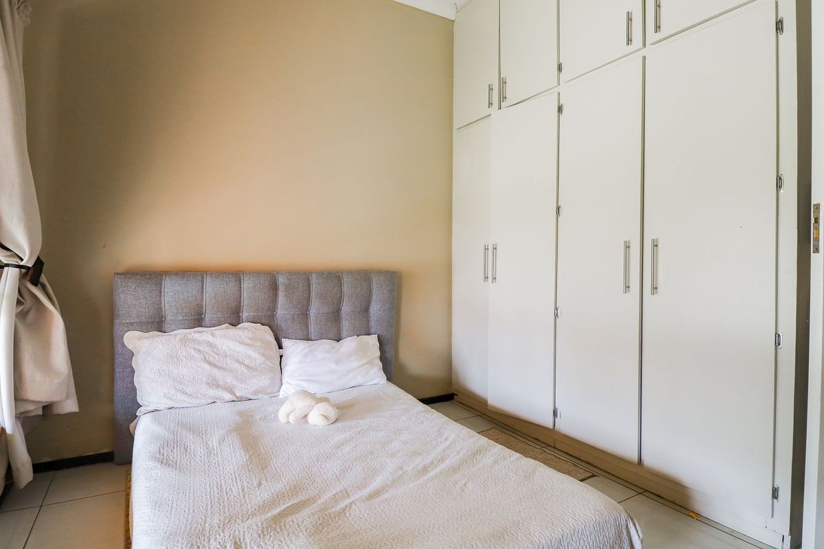 A bedroom featuring neutral walls, tiled flooring, and extensive built-in cupboard storage.