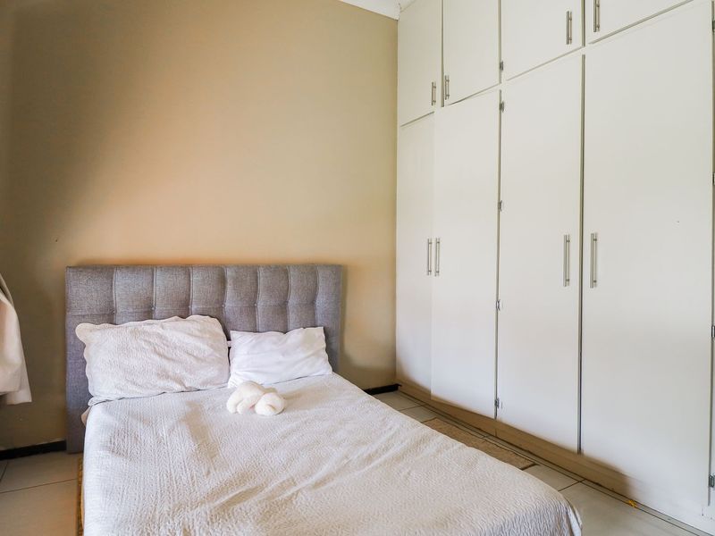 A bedroom featuring neutral walls, tiled flooring, and extensive built-in cupboard storage.