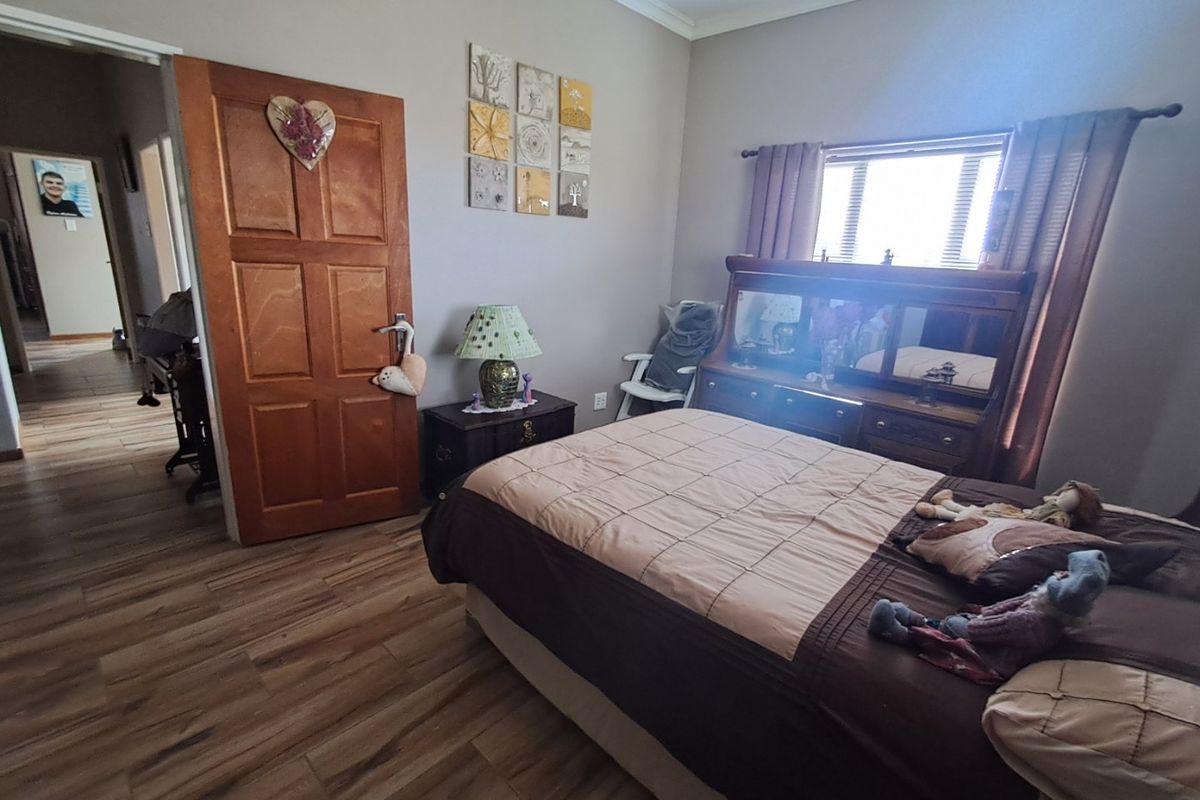 A bedroom featuring laminate flooring, a timber door, and a window with curtain rods, providing a functional living space.