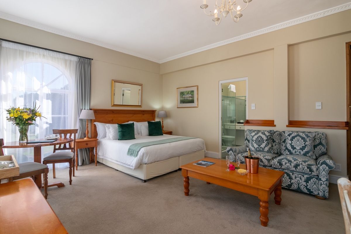 Spacious bedroom featuring an arched window, crown molding, and an integrated en-suite bathroom with neutral wall finishes and carpeted flooring.