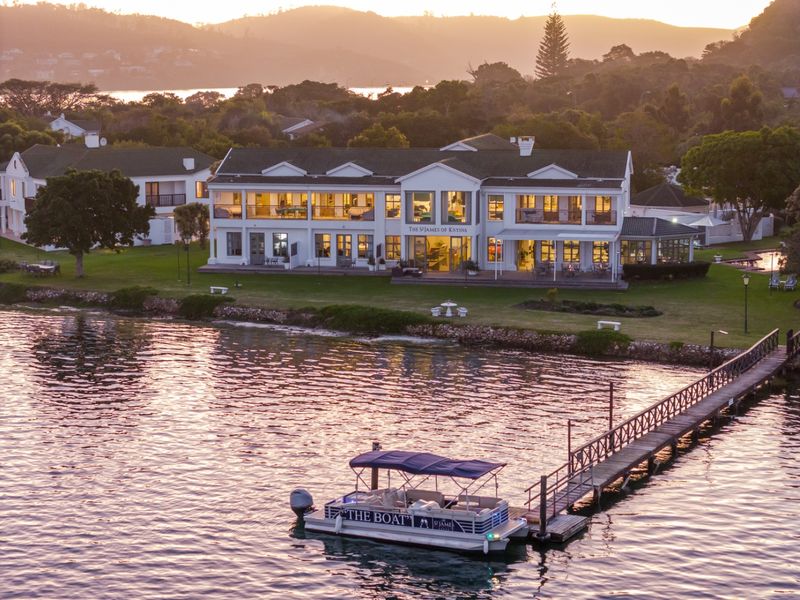 Aerial view of a luxury waterfront commercial property featuring a private jetty, expansive landscaped grounds, and multi-level building with balconies overlooking the water.