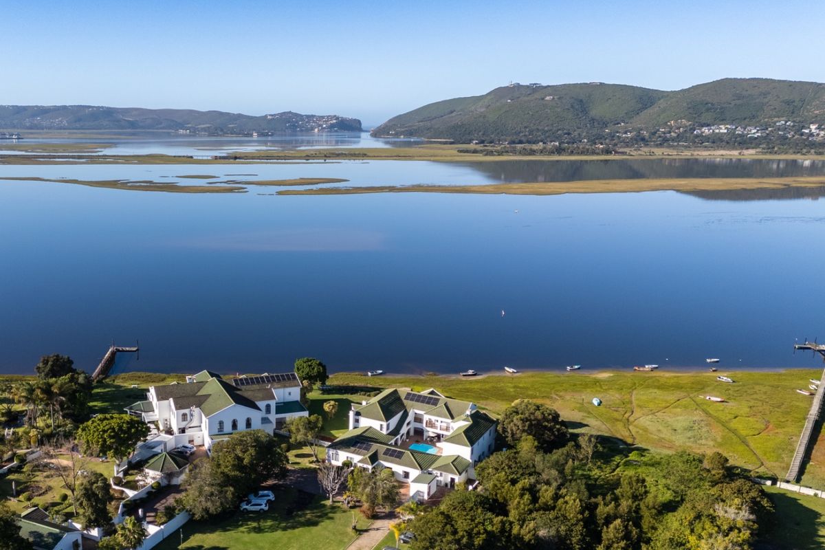 Aerial view of a large waterfront commercial property featuring multiple buildings, a swimming pool, solar panels, and direct access to the lagoon.