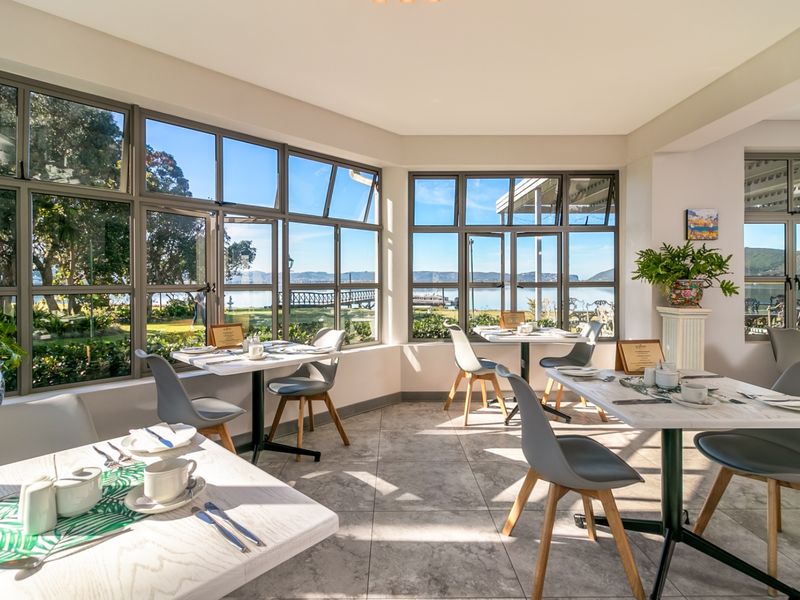 Bright open-plan dining area featuring expansive aluminium-framed windows with scenic views and modern tiled flooring.