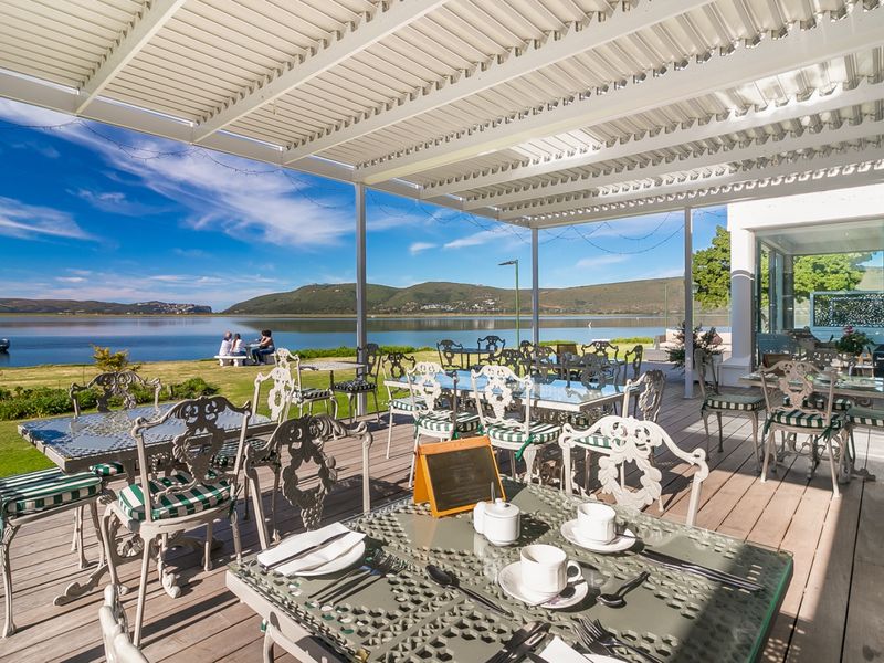Spacious outdoor patio featuring timber decking and a modern louvre roof system, offering panoramic waterfront views.