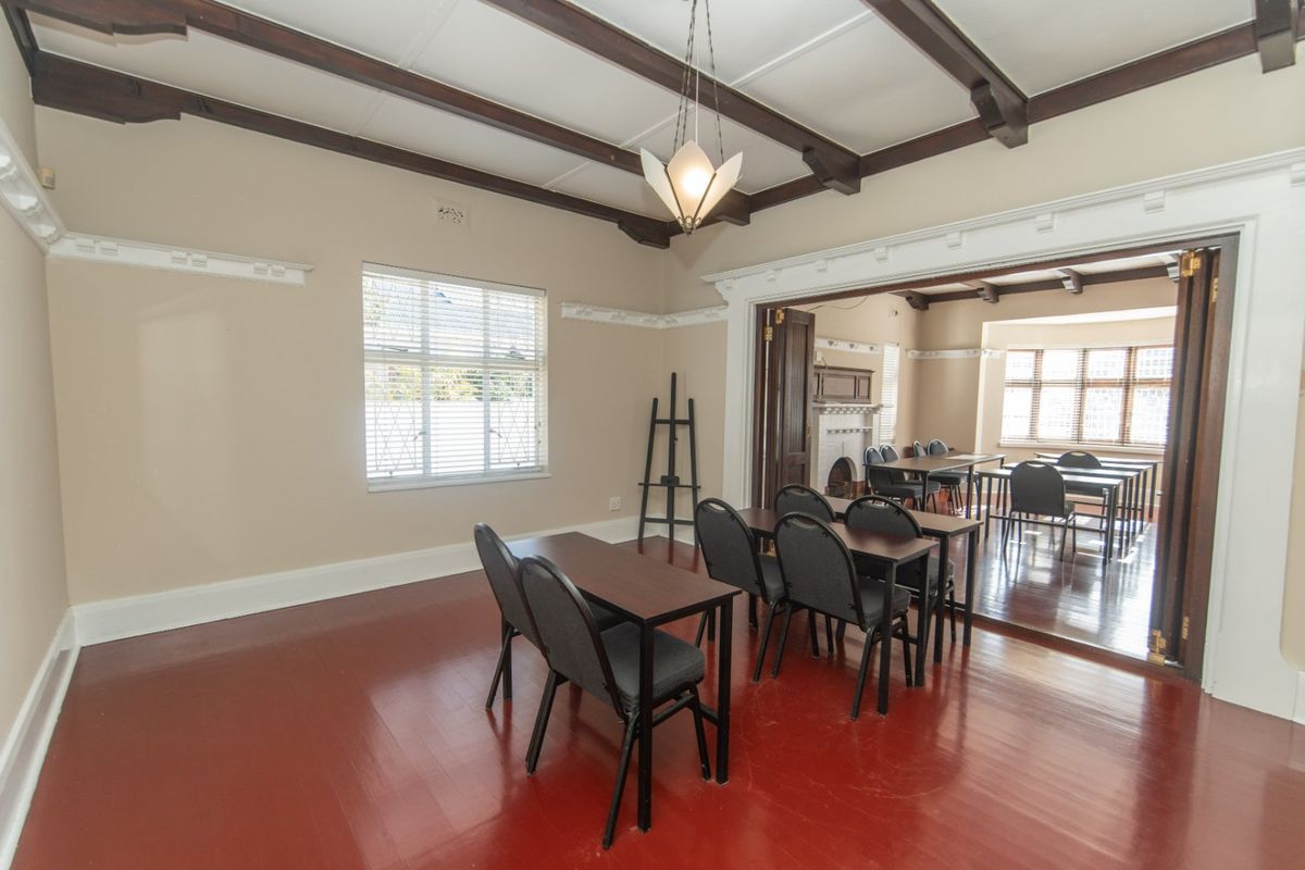 Spacious living area featuring exposed timber ceiling beams, decorative molding, hardwood floors, and bi-fold doors connecting to an adjacent room with a fireplace.
