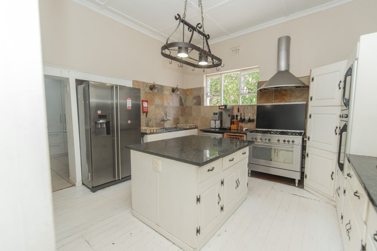 A functional kitchen featuring a central island with granite countertops, stainless steel appliances, stone tile backsplash, and ample built-in cabinetry.