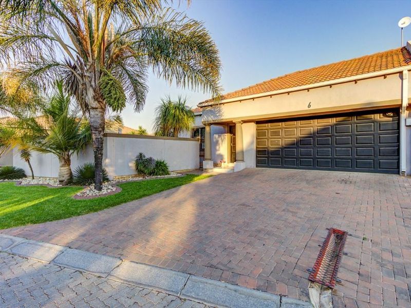 Front exterior view of the townhouse featuring a paved driveway, double garage, and landscaped garden area.
