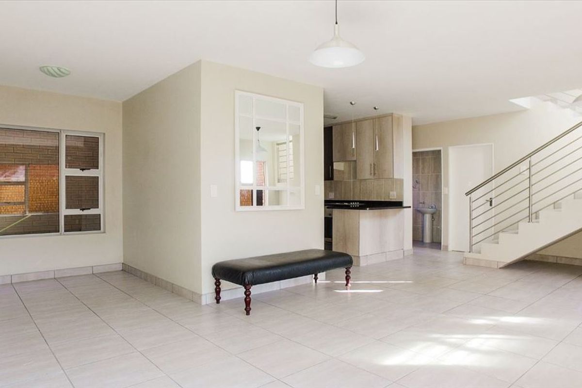 Spacious open-plan living area featuring tiled floors, a modern staircase with stainless steel balustrades, and an integrated kitchen with granite countertops.