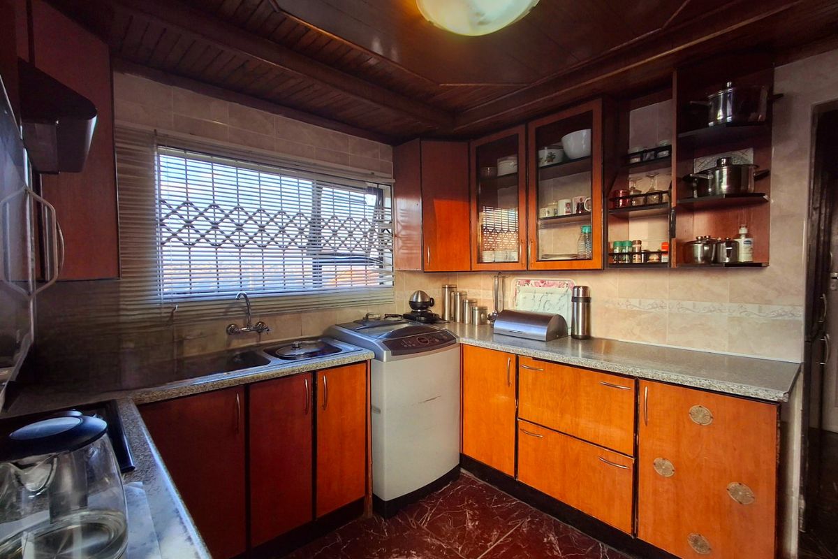 A functional kitchen featuring timber cabinetry, laminate countertops, tiled splashbacks, and a timber ceiling, offering a traditional aesthetic with potential for modern updates.