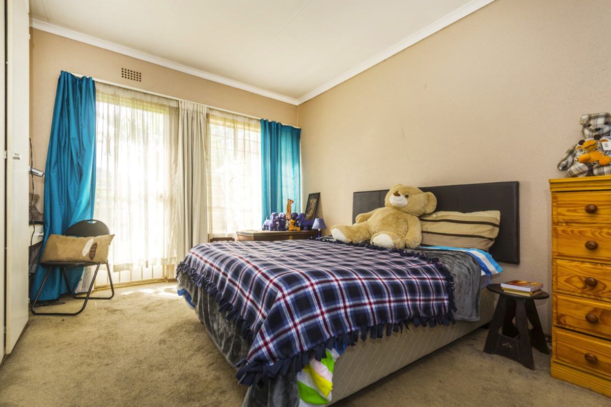 A bedroom featuring carpeted flooring, a built-in cupboard, and a sliding glass door providing natural light.