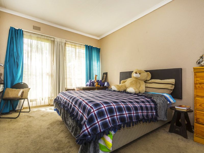 A bedroom featuring carpeted flooring, a built-in cupboard, and a sliding glass door providing natural light.