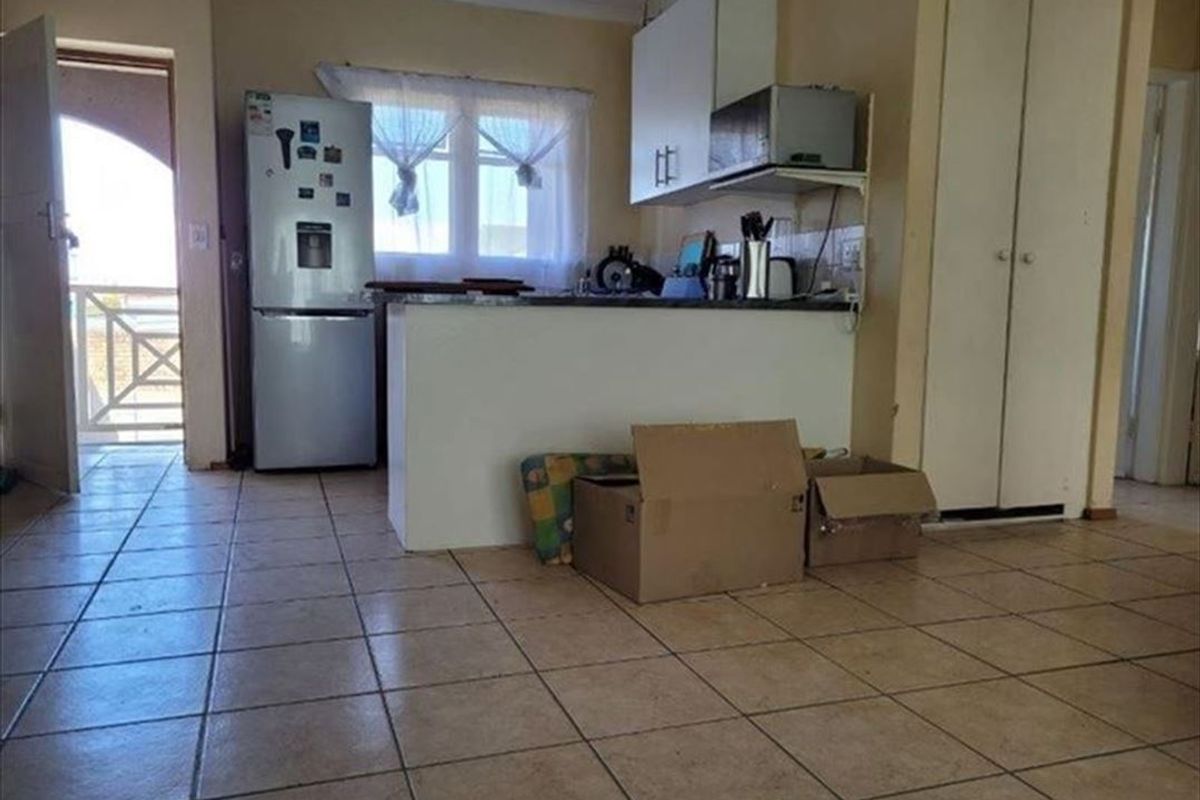 Open plan kitchen area featuring tiled flooring and built-in cabinetry, with direct access to an outdoor balcony space.