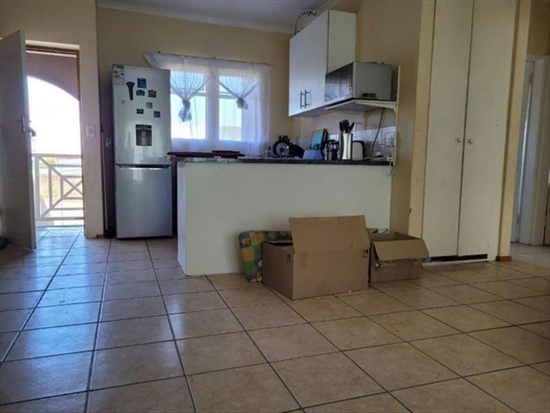 Open plan kitchen area featuring tiled flooring and built-in cabinetry, with direct access to an outdoor balcony space.
