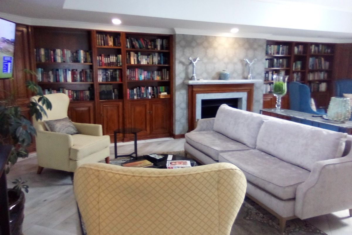 A comfortable living room featuring extensive built-in wooden bookshelves and a central fireplace with a decorative mantelpiece.