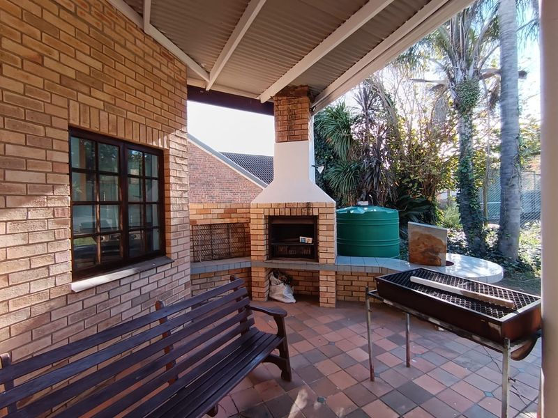 Covered patio area featuring a built-in brick braai, tiled flooring, and direct access to the garden.
