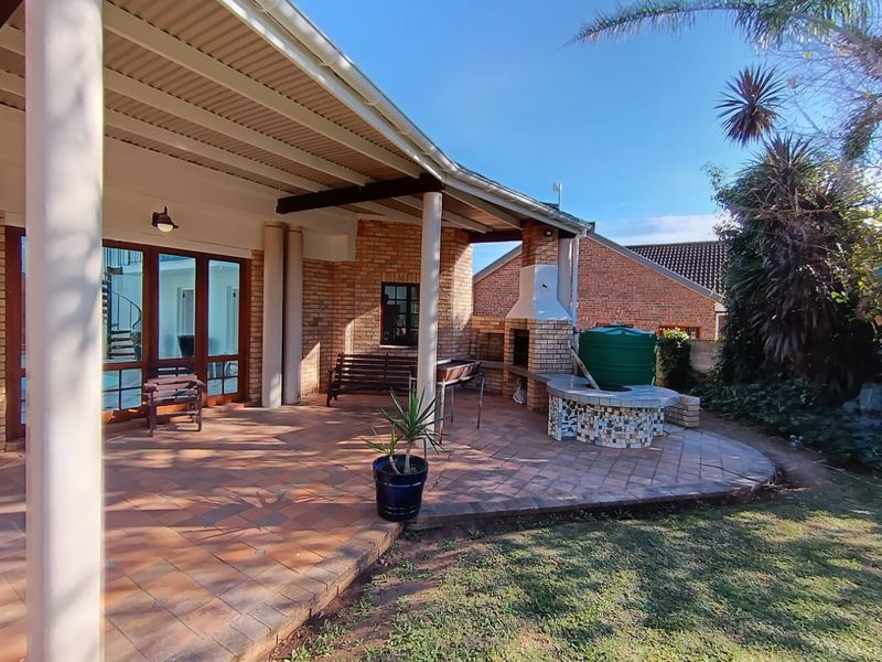 A covered patio area featuring brick construction, a built-in braai, and tiled flooring, providing an ideal space for outdoor entertaining.