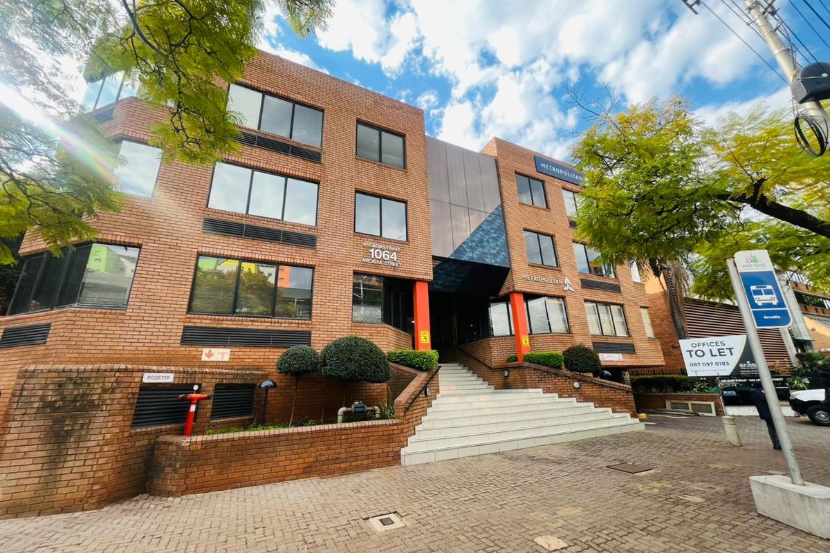 Front elevation of a multi-story commercial office building featuring a brick facade, glass accents, and a prominent tiled entrance staircase.