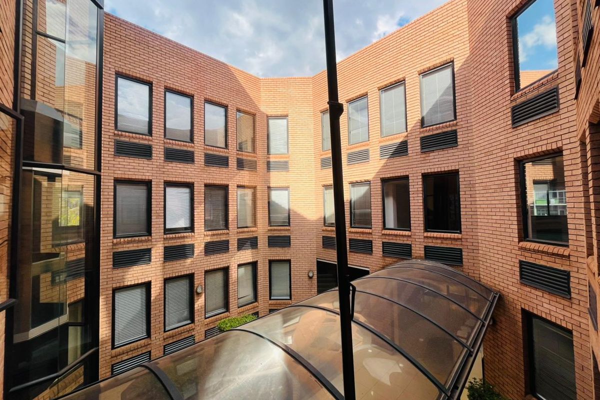 A view of the commercial building's central courtyard featuring a brick facade, multi-level windows, and a curved overhead canopy.