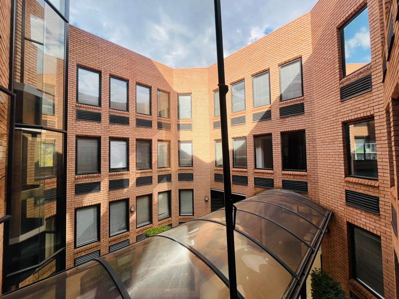 A view of the commercial building's central courtyard featuring a brick facade, multi-level windows, and a curved overhead canopy.