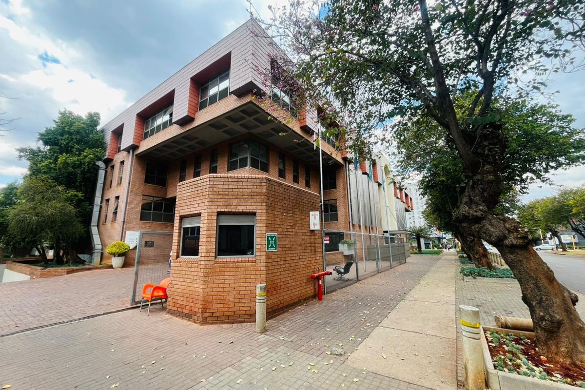 A commercial property featuring a brick facade, a dedicated security guard house, and paved exterior access with perimeter fencing.
