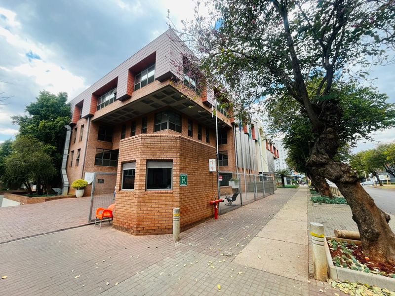 A commercial property featuring a brick facade, a dedicated security guard house, and paved exterior access with perimeter fencing.