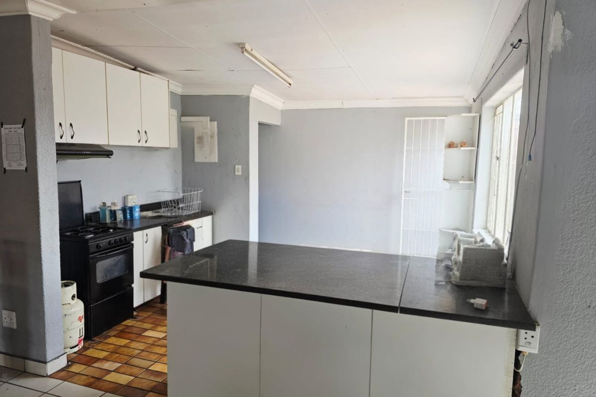 A dated kitchen featuring built-in cabinetry, a central island, and tiled flooring, requiring cosmetic updates and repairs to the ceiling and wall finishes.