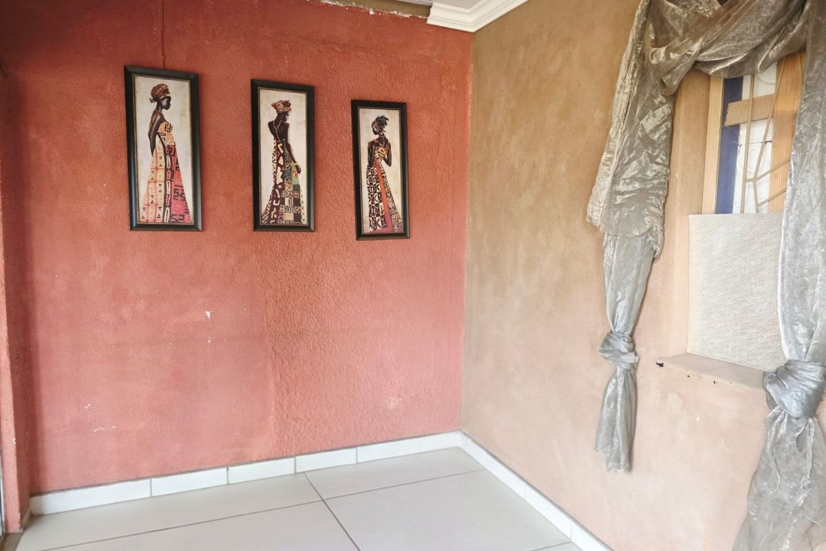 An empty living area featuring tiled flooring and textured walls, requiring cosmetic updates to improve the overall finish and aesthetic appeal.