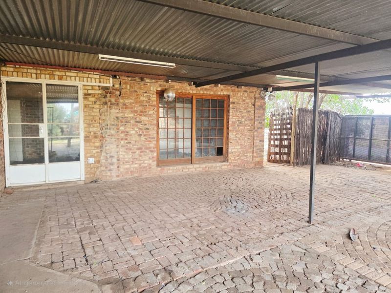 A covered outdoor patio area featuring brick paving, exposed brick walls, and a corrugated metal roof, requiring some maintenance and repair.