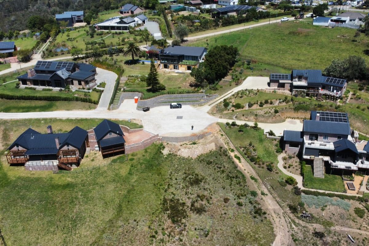 An aerial view of a residential estate featuring multiple modern homes with solar panels, paved driveways, and established landscaped grounds.