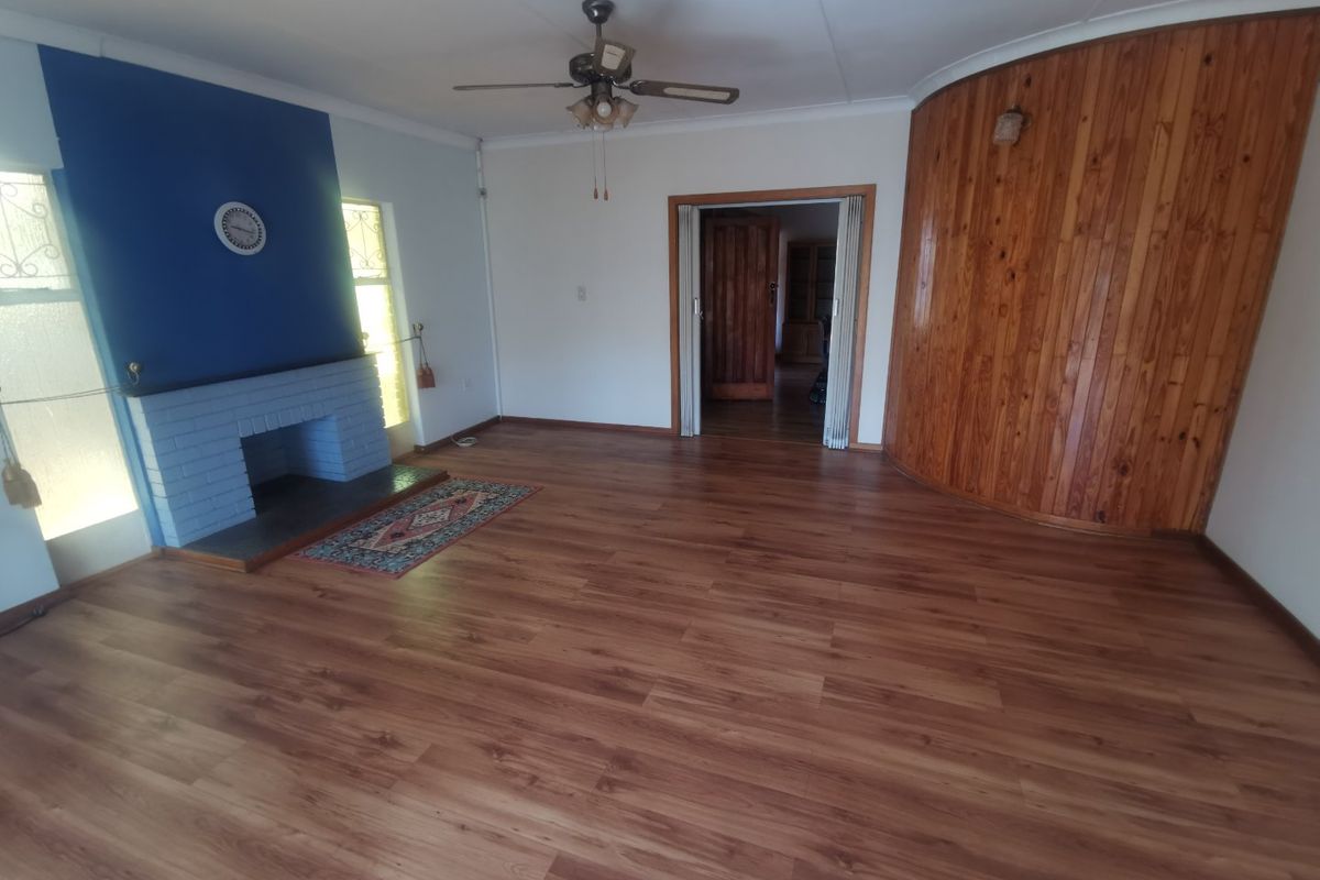 Spacious living room featuring a brick fireplace, wood-look laminate flooring, and a curved timber-paneled feature wall.