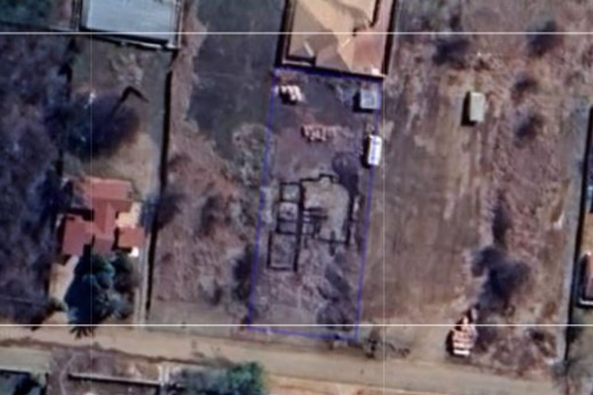 Aerial view of a vacant residential plot featuring a foundation slab and boundary fencing in a suburban neighborhood setting.